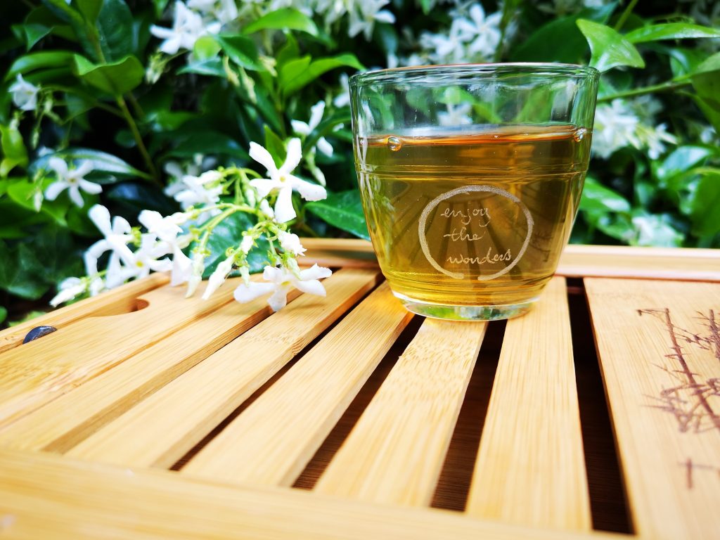A cup of tea elegantly placed on a wooden platter, with greenery in the background, highlighting its benefits for heart health.