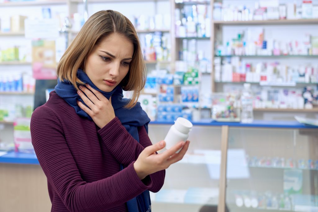 Side view of woman with sore throat, choosing medicines for disease treatment.