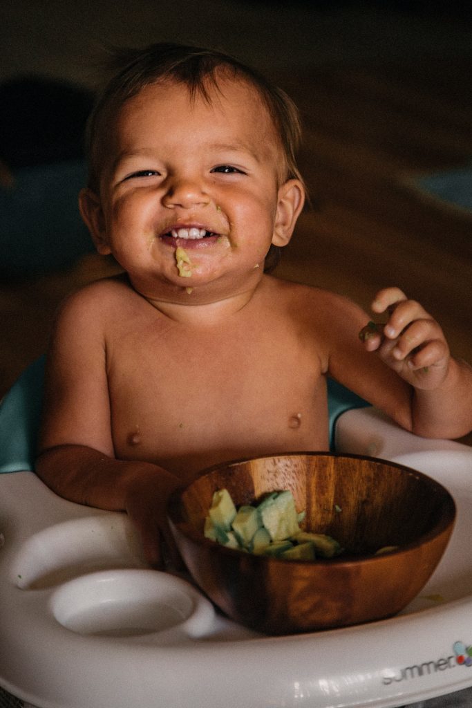 A cheerful, cute toddler munching on vegetables.