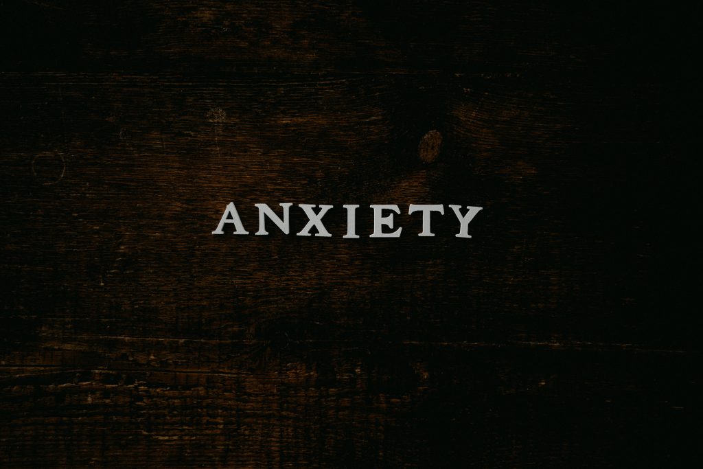 The word 'ANXIETY' arranged using plastic letter moldings on a wooden surface.