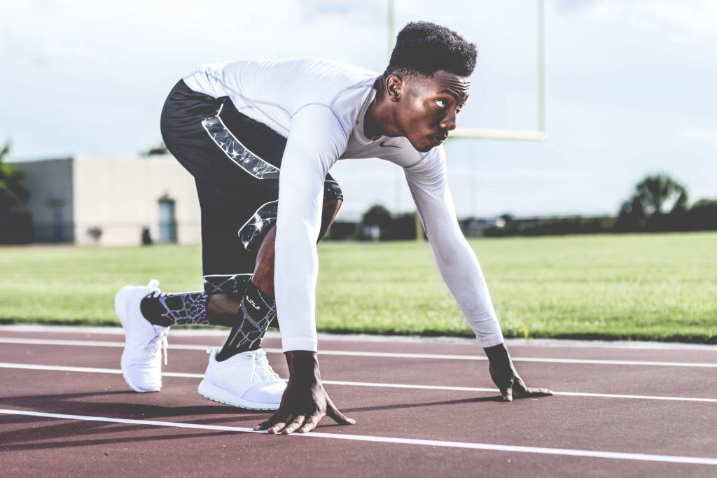 An athlete preparing to start his run on a running track.