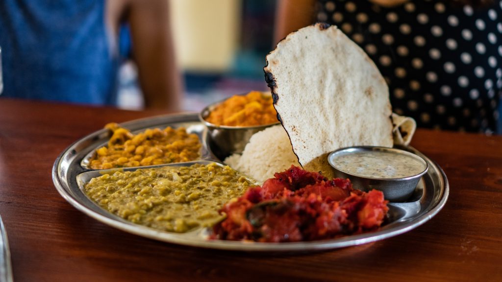 An Indian thali, including delicious vegetable dishes, chicken, rice, rotis, and kheer, indicating a fully balanced, sumptuous meal.