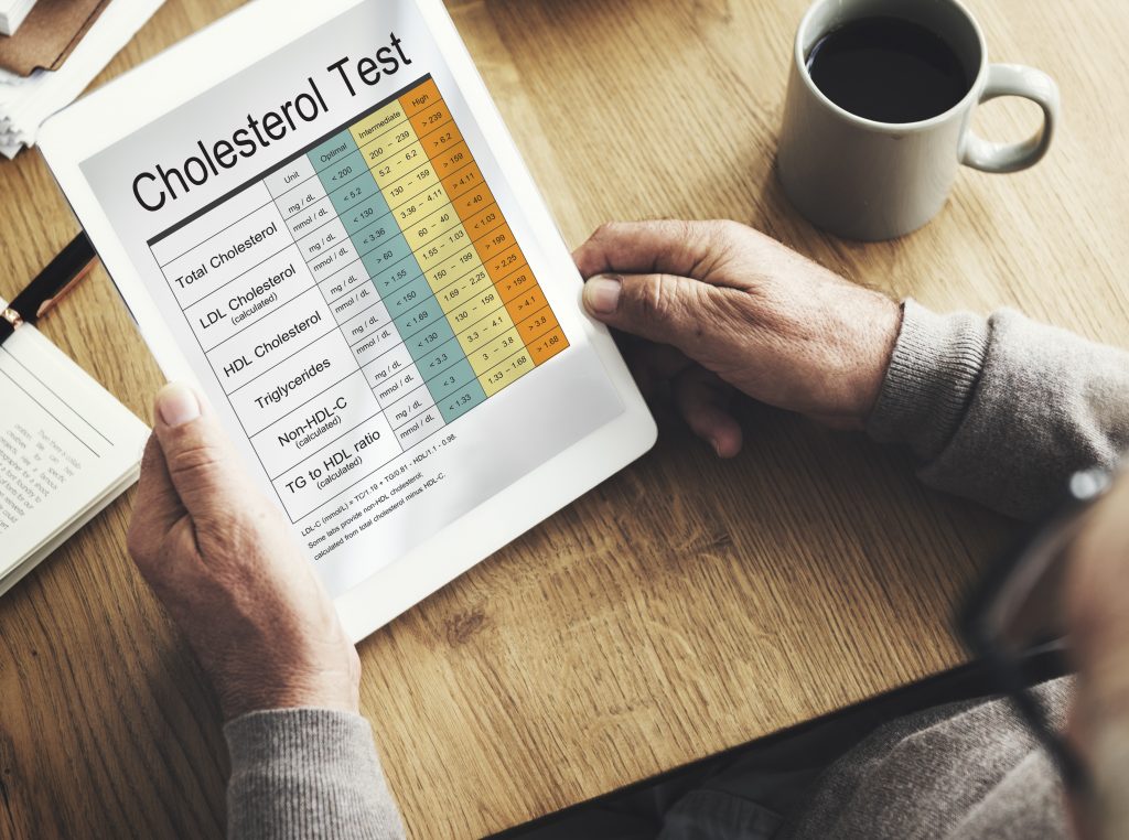 Close-up shot of a man holding a tablet and reading his cholesterol test report.