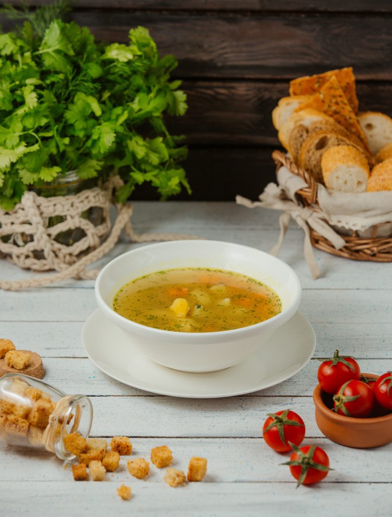 A rich, flavorful chicken soup in a bowl, surrounded by its ingredients.