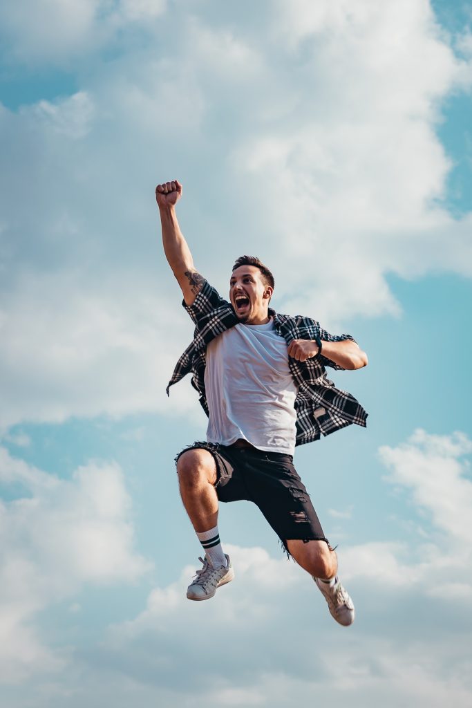 An energetic young man jumping high in the air with joy.