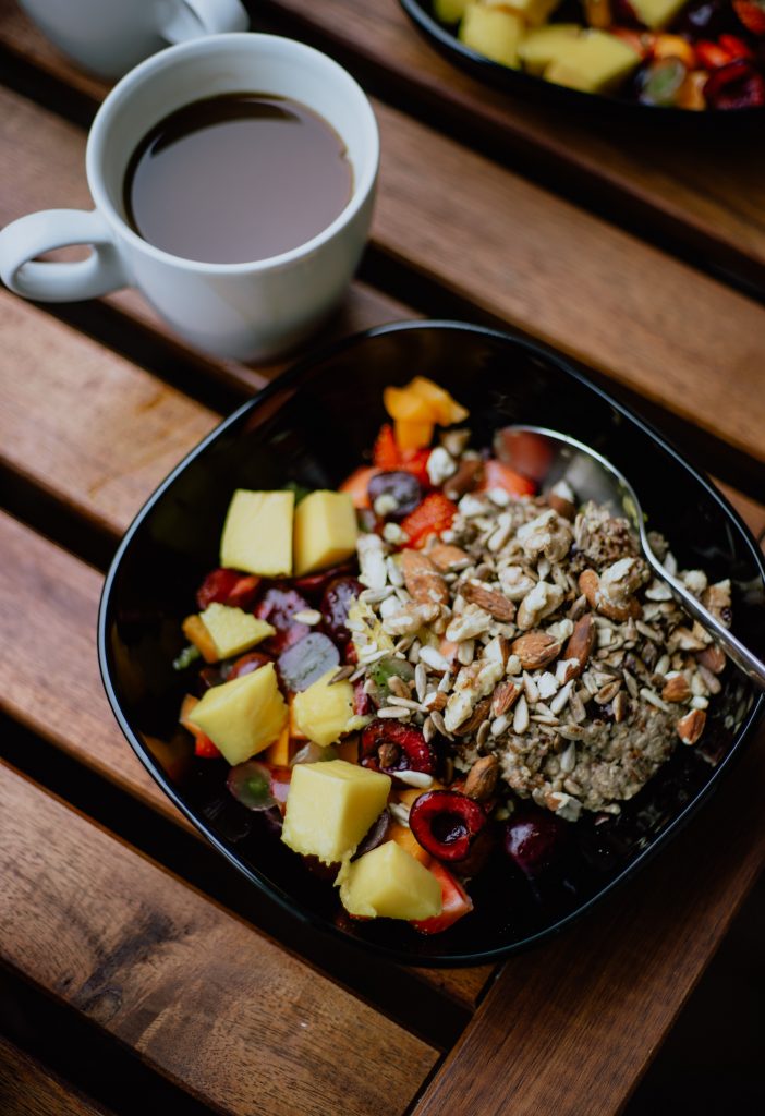 A bowl of salad containing fruits, berries, and oats, featuring high-fiber foods.