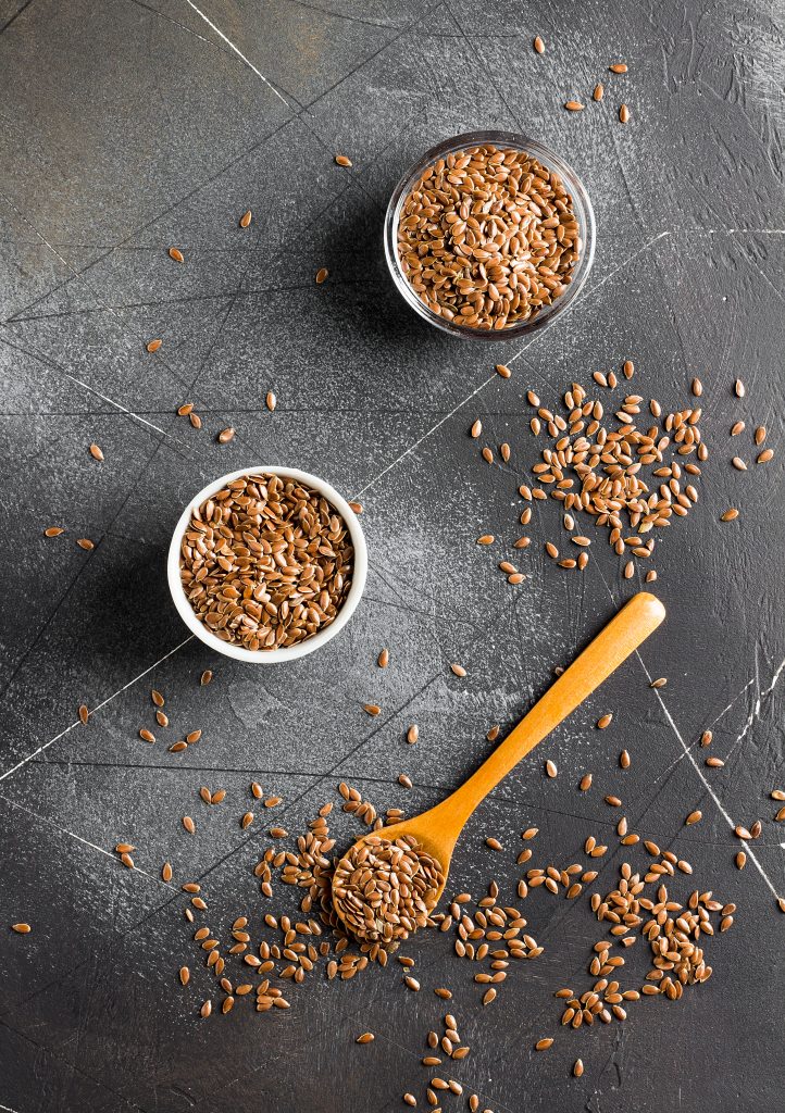 Flax seeds, a superfood and healthy organic food, in a bowl with some scattered around