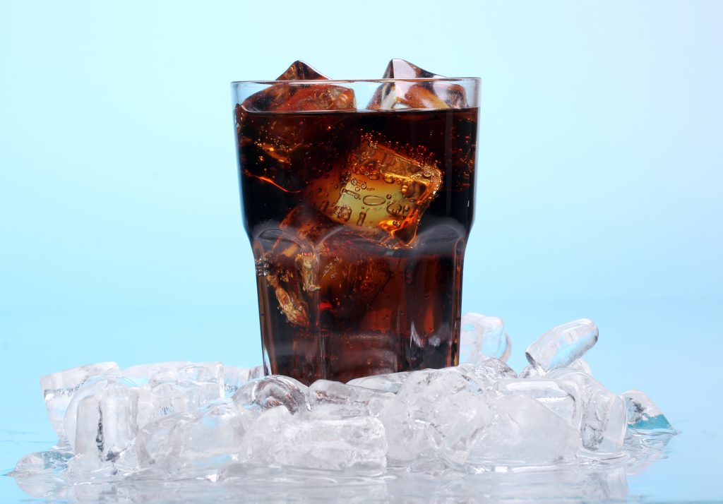 An elegant shot of a glass filled with coke and ice cubes, capturing its refreshing appeal.
