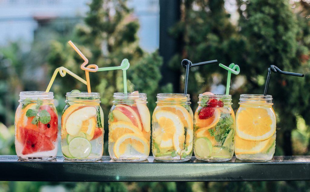 Jars filled with colorful fruit-infused water and straws, highlighting the importance of avoiding liquids before bed.