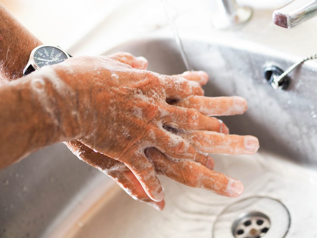 A close-up shot of a man washing his hands with soap in a sink.