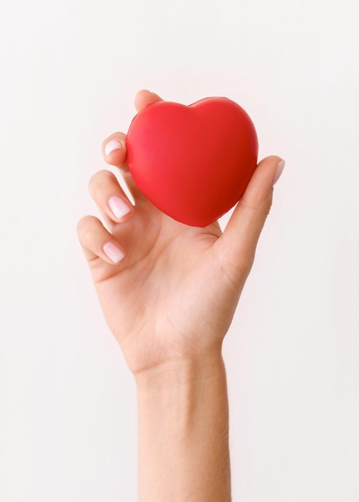 A close-up shot of a hand holding a heart, emphasizing the importance of lowering cholesterol to promote heart health