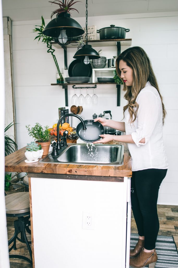 A woman washing plates by the sink, cleaning them with care.