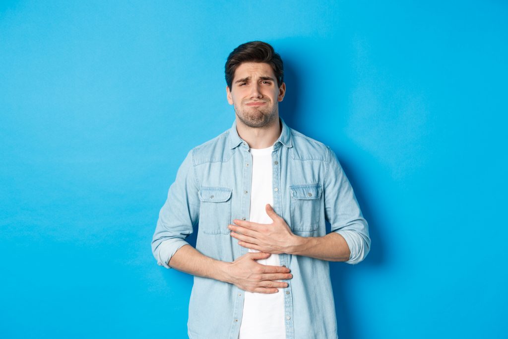 A man clutching his chest in discomfort, visibly distressed due to severe heartburn.