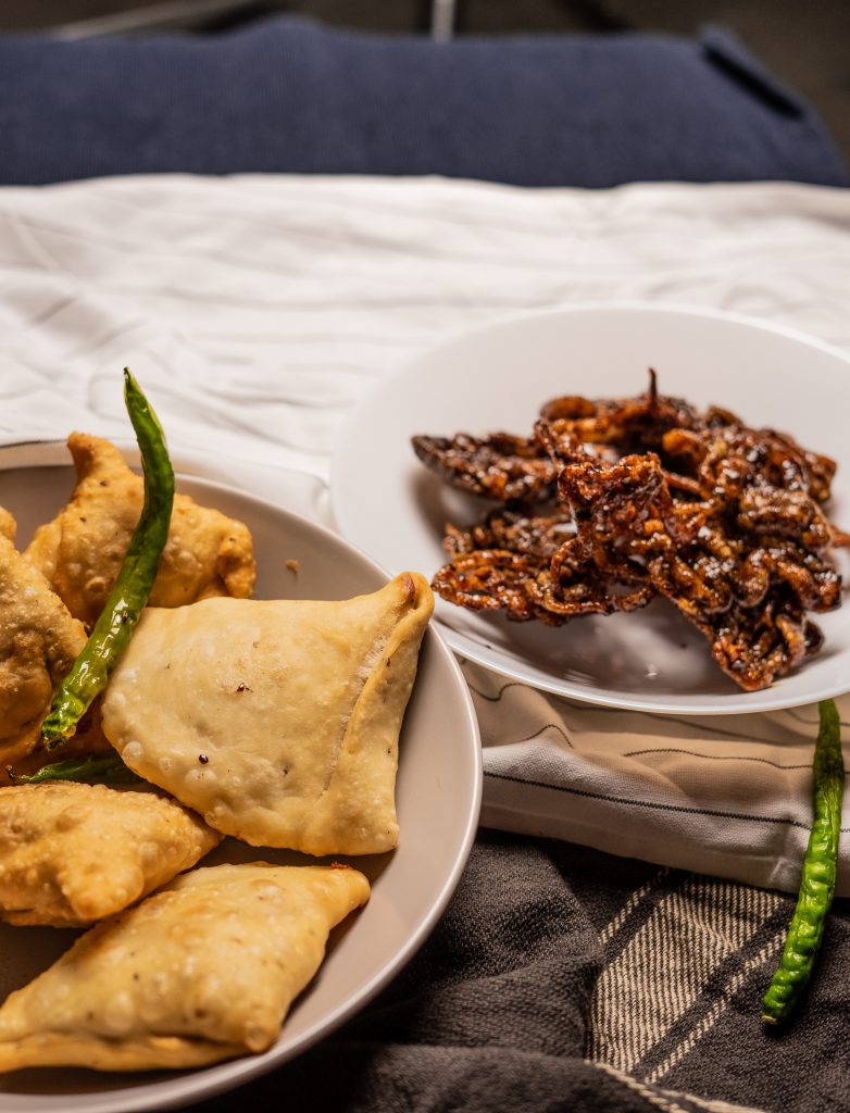 Plates neatly arranged with high-calorie snacks like samosas and fritters, highlighting their role in increasing blood triglyceride levels.
