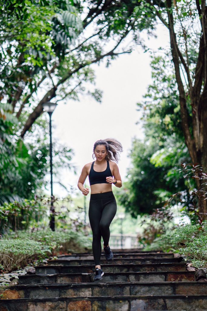 A young woman jogging in a park, highlighting the importance of exercise in maintaining healthy cholesterol levels