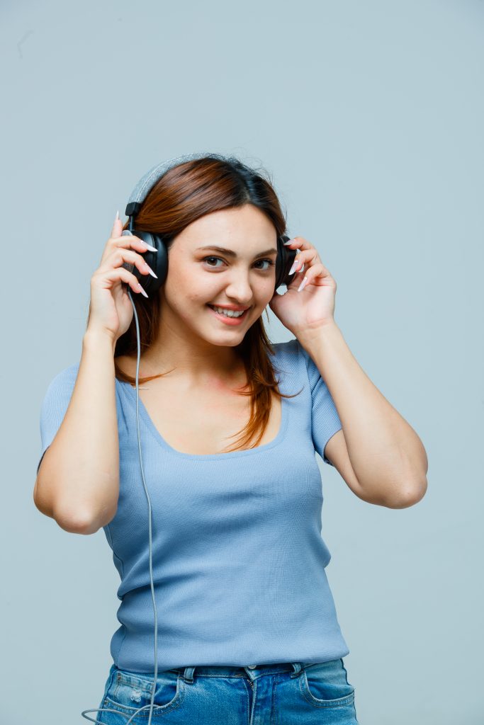 A young girl wearing headphones, enjoying music and visibly in a good mood.