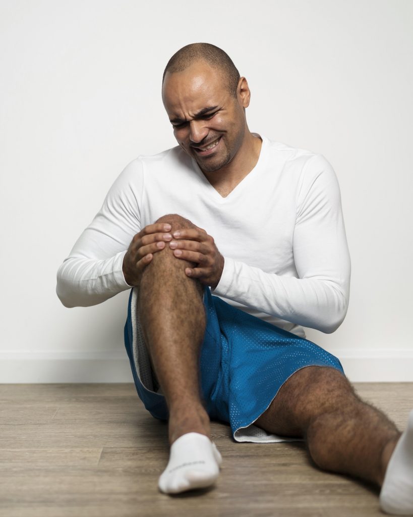 A man visibly in distress, experiencing severe knee pain.
