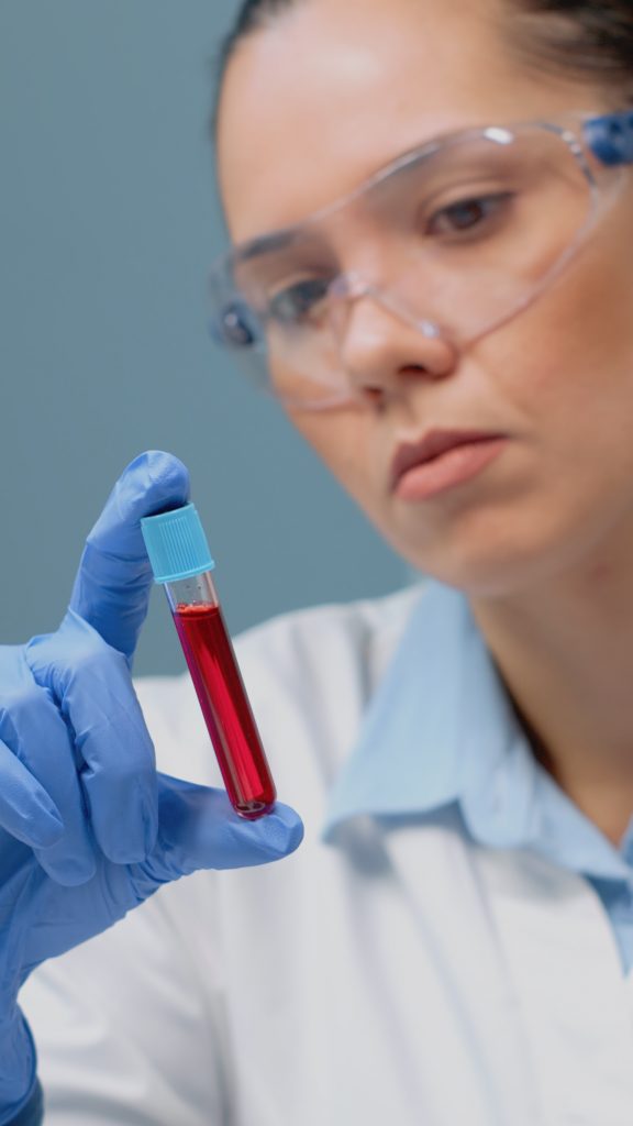 A healthcare worker holding a tube filled with blood, conducting a screening for calcium deficiency.