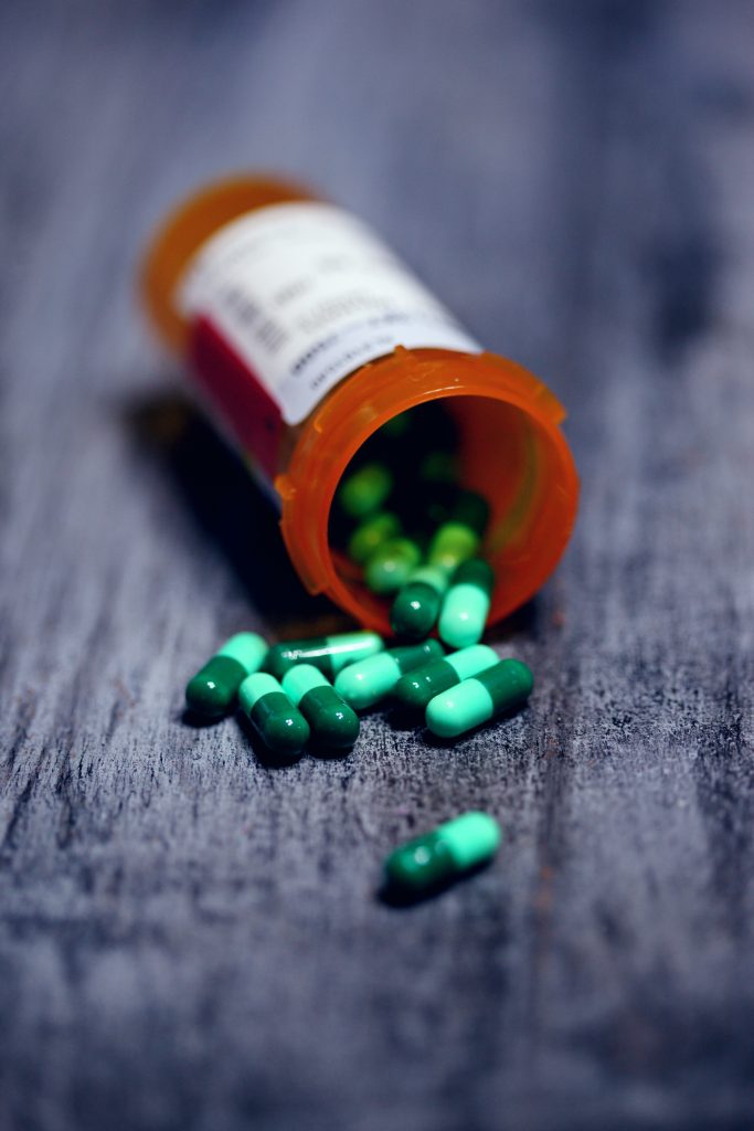An aesthetic shot of a medicine bottle with capsules spilled on the surface, emphasizing the importance of medications in aiding recovery.