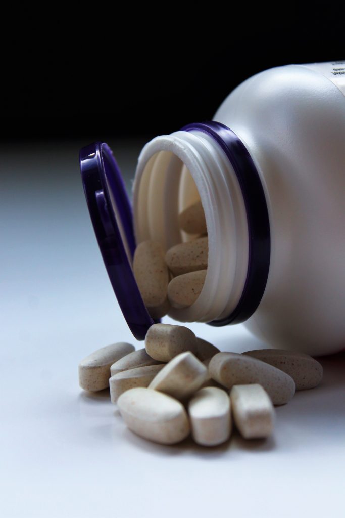 A bottle of calcium supplements lying open, with some pills spilled out.