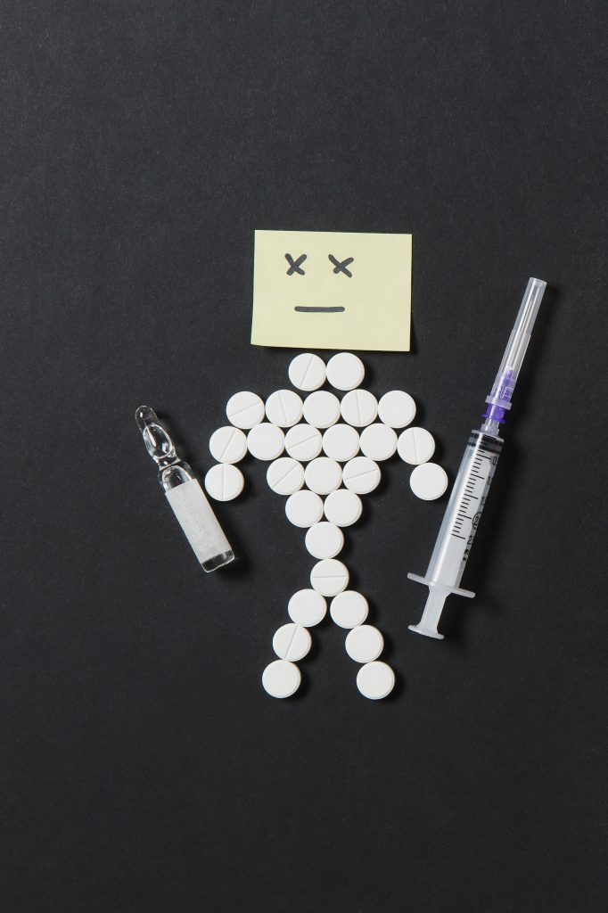 Medicines, insulin, and a syringe arranged in a playful way to represent a man.