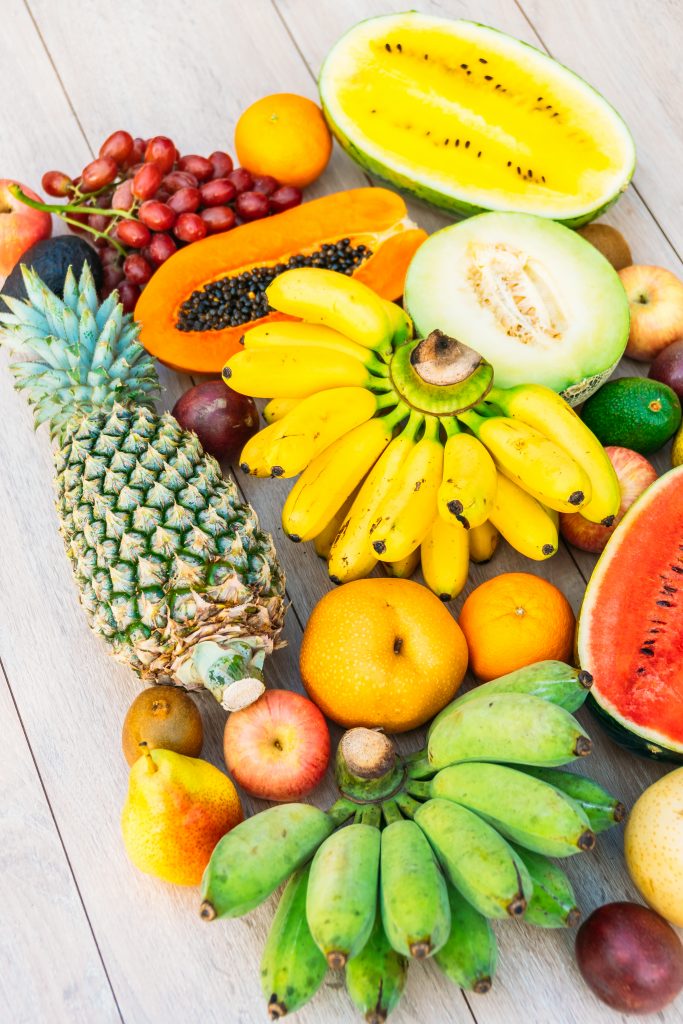 Assorted fruits—apple, banana, orange, and others—displayed on a wooden surface.