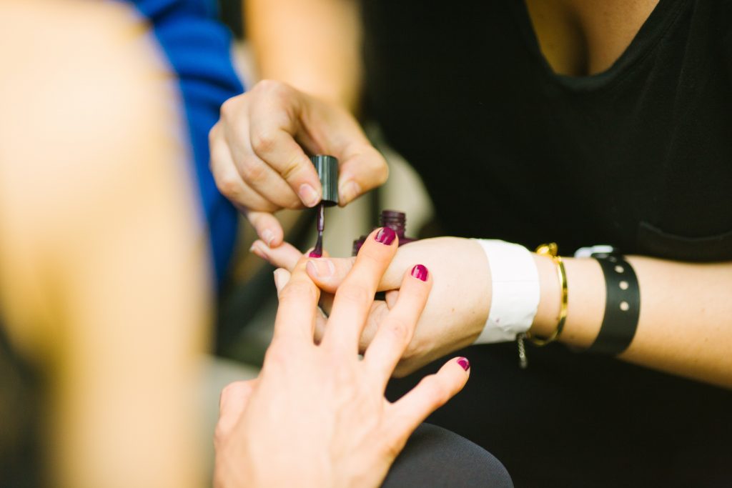 A woman having nail polish applied during her manicure session.