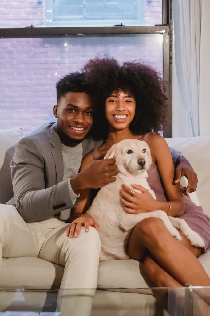 A couple happily posing with their beloved pet, illustrating how the deep bond with their pets strengthens their connection with each other.