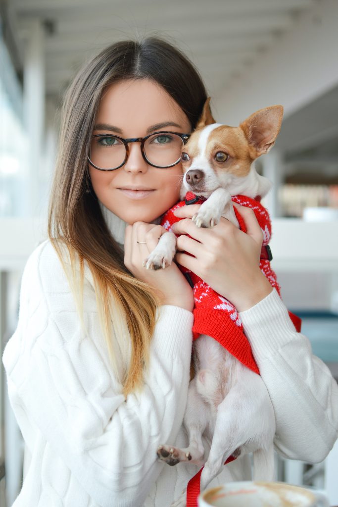 A candid shot of a woman posing with her pet dog.