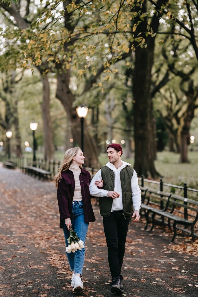 A couple strolling in a park surrounded by trees, suggesting the importance of spending time in nature for improved mental health.