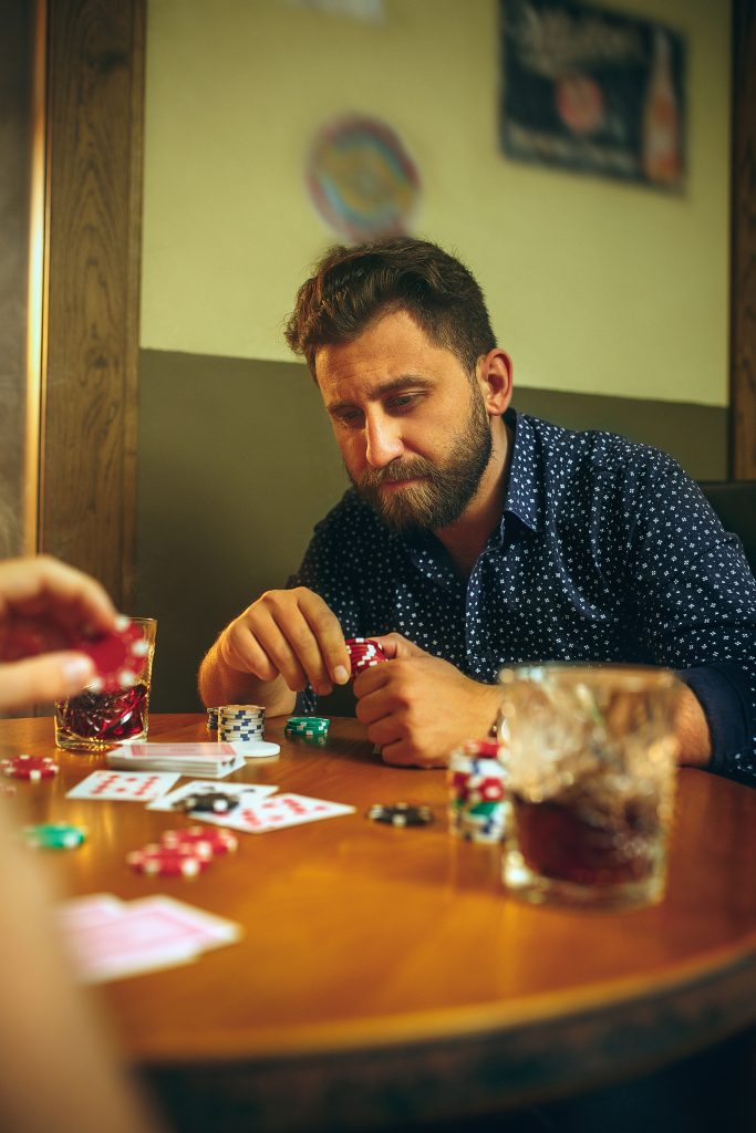 A close up shot of men playing poker game and consuming alcohol, highlighting how gambling problems can contribute to depression.