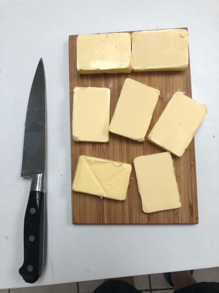 Neatly cut blocks of butter with a knife placed nearby, highlighting how saturated fats can raise LDL or “bad” cholesterol.