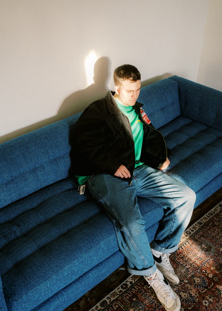 A young man sitting inactive on a sofa, appearing to be in deep thought.