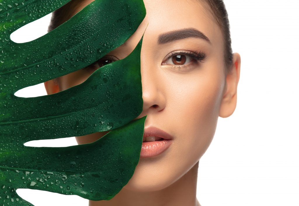 A stunning close-up photograph of a female model with clear, glowing skin,masked by a leaf, clearly highlighting the effects of quitting alcohol.