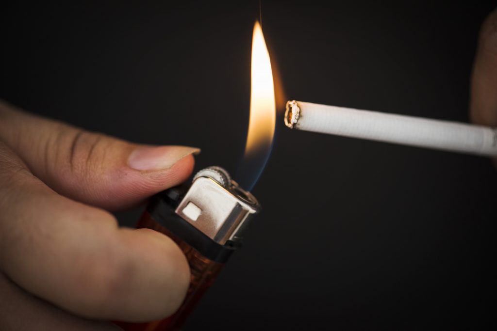 A cigarette being lit with a lighter, symbolizing the harmful effects of smoking.