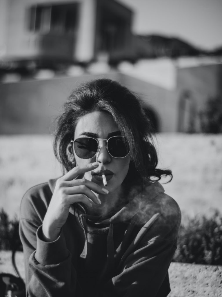 A woman smoking a cigarette, depicting the harmful effects of smoking on health.