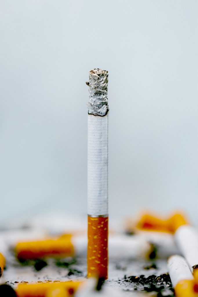 Close-up of a half-smoked cigarette, highlighting the warning that smoking lowers "good" cholesterol levels (HDL).