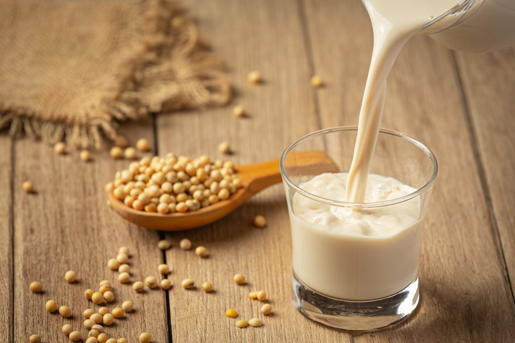 Soy milk poured into a glass with soybeans on a wooden table, highlighting its role as a magnesium source.