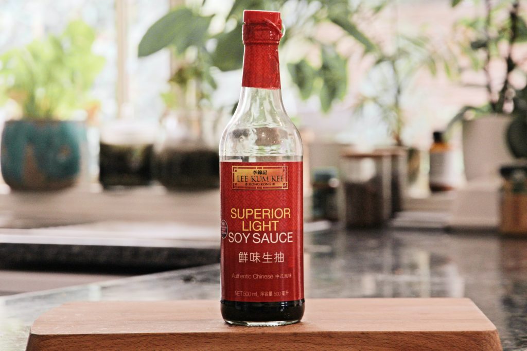 An in-focus shot of a bottle of soy sauce, elegantly placed on a wooden platter.