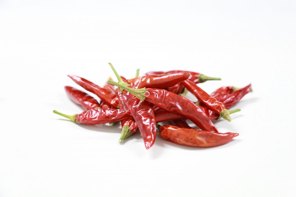 An aesthetic display of red chillies against a white background.