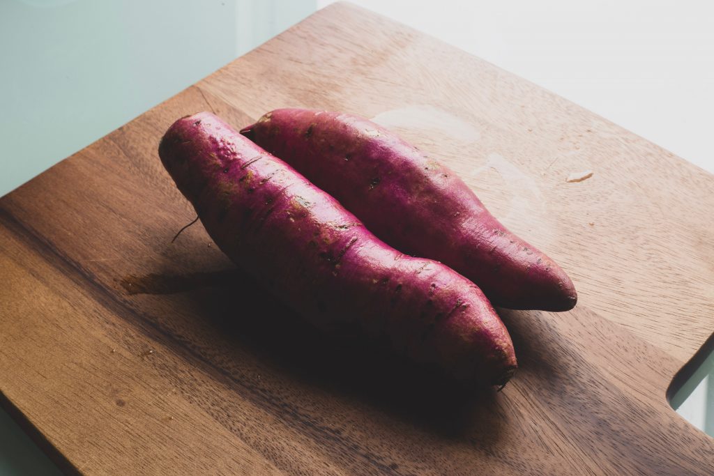 Sweet potatoes, rich in beta-carotene, B vitamins, and minerals, neatly arranged on a wooden platter.