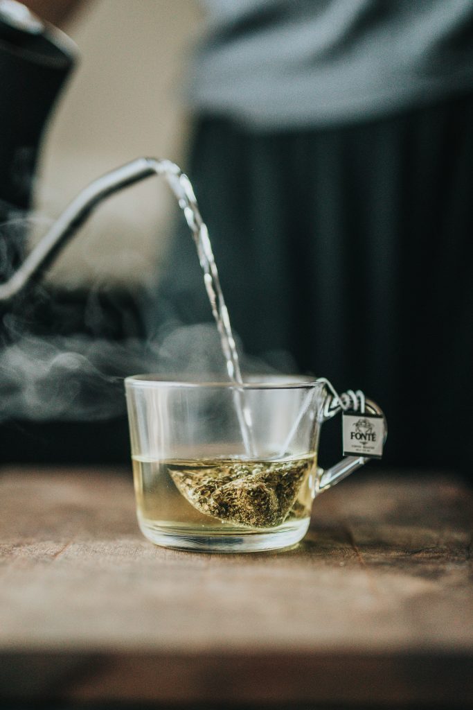 Hot water being poured from a kettle into a cup with a tea bag.