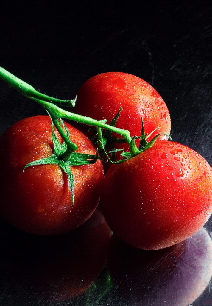 An aesthetic shot of ripe tomatoes against a black background, highlighting their powerful antioxidant properties.