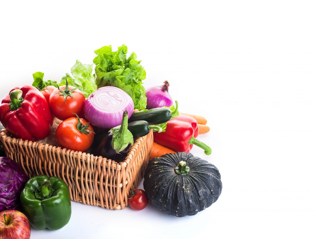 An assortment of fresh vegetables like pumpkin, onion, capsicum, lettuce, carrots, and tomatoes elegantly arranged in a basket.