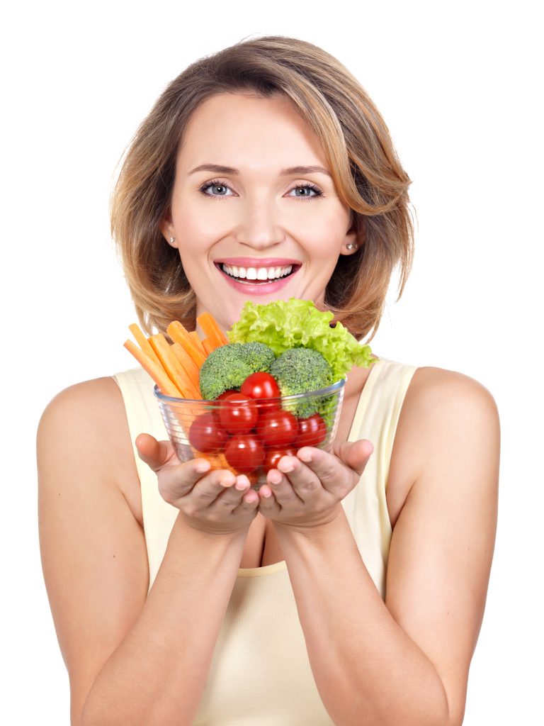 A young woman holding a bowl filled with raw vegetables.
