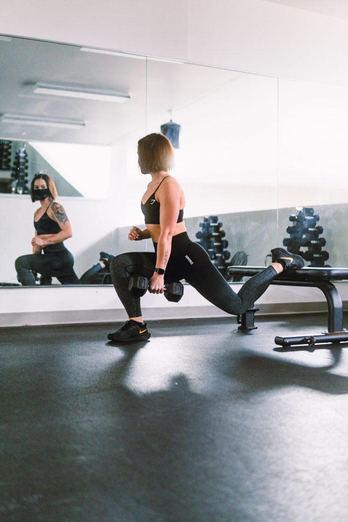 A woman lifting weights in a gym, emphasizing the role of weightlifting in a successful weight loss journey.