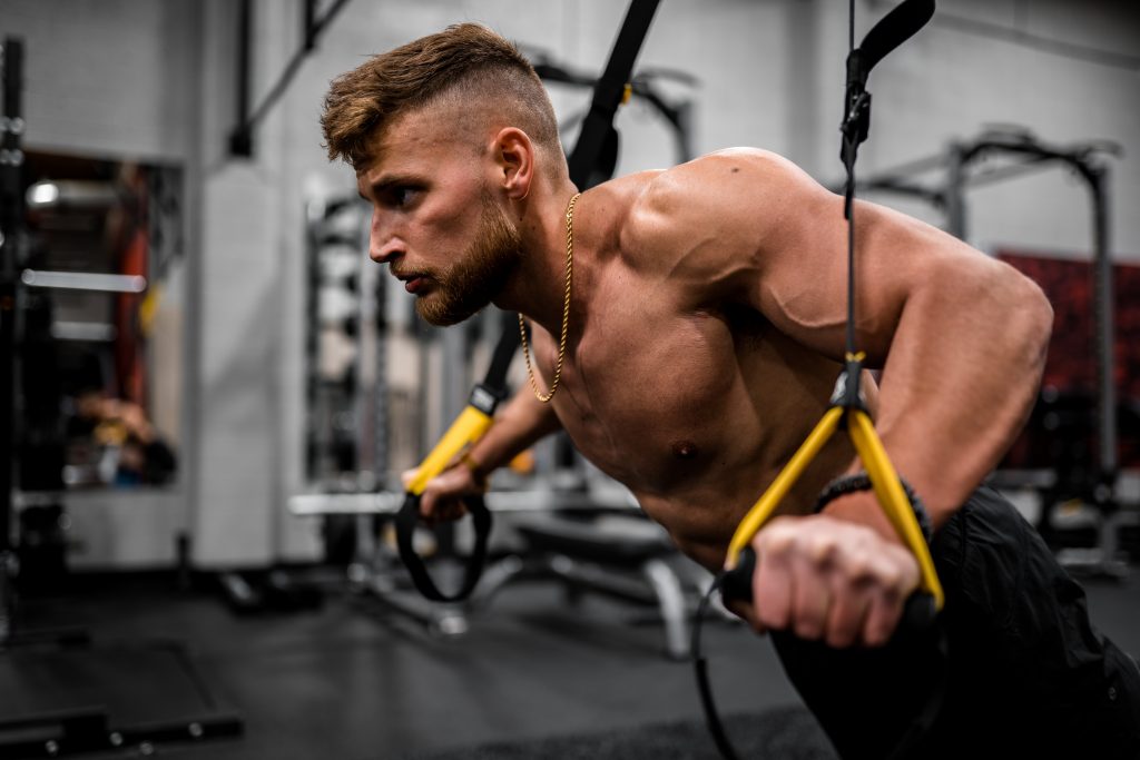 A man appearing focused and intensely working out in a gym