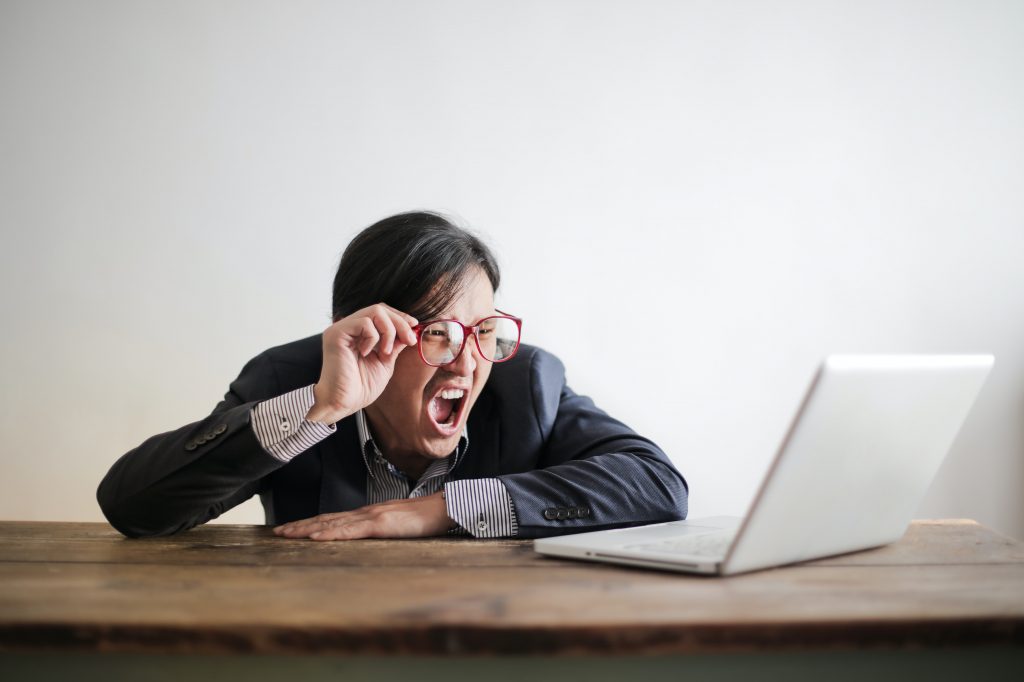 A man in a suit yawning at his desk, a sign of anemia linked to kidney failure, causing low oxygen levels in the brain.