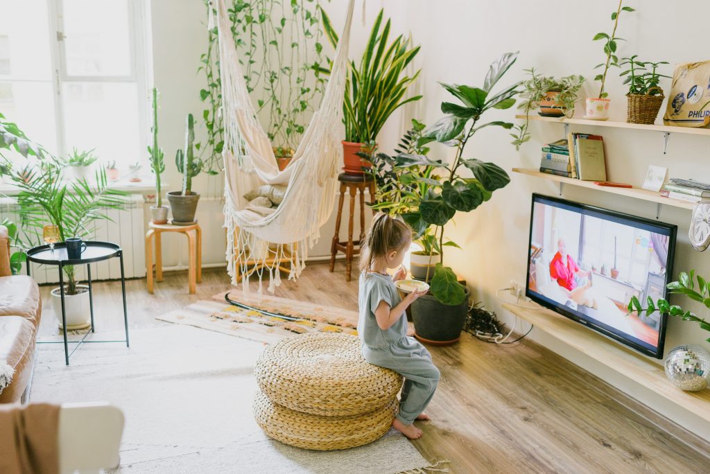 Child sitting on a woven stool watching TV, highlighting how mindful eating can be a powerful tool for weight management.