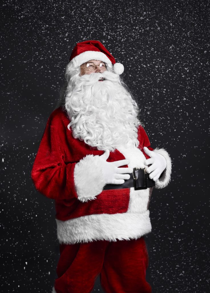 Santa in a red and white suit, holding a belt with a black buckle, set against a starry night sky.